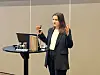 Kristine Flaatten Furu fra KLP står ved rundt bord med PC og holder presentasjon i konferansesal.
