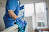 Female nurse cleaning the bed after patients in hospital ward.