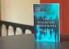 En blå bok med tittelen «Det kollektive arbeidslivet» står på et bord i et innemiljø.