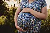Gravid kvinne i blomstrete kjole utendørs